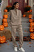woman wearing beige cotton-blended two-piece tracksuit standing on Halloween decorated porch with pumpkins and skeletons